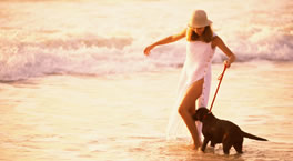 Femeie cu câine pe plajă.